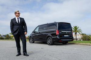 Executive transportation service showcasing a black Mercedes van in an outdoor setting.