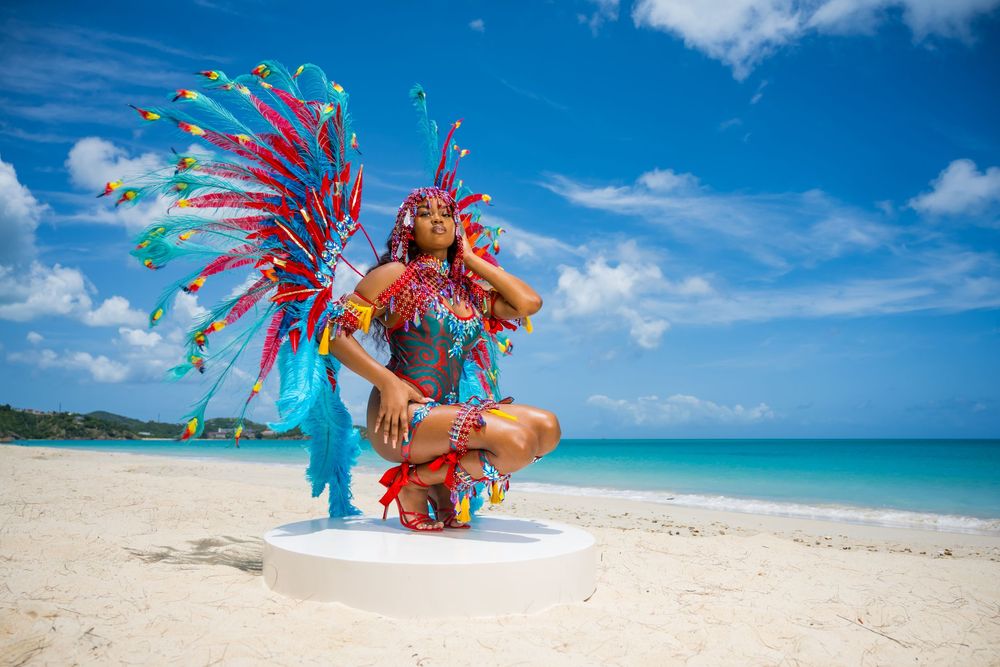 Colorful carnival costume with feathered wings and beaded details photographed on sandy beach.