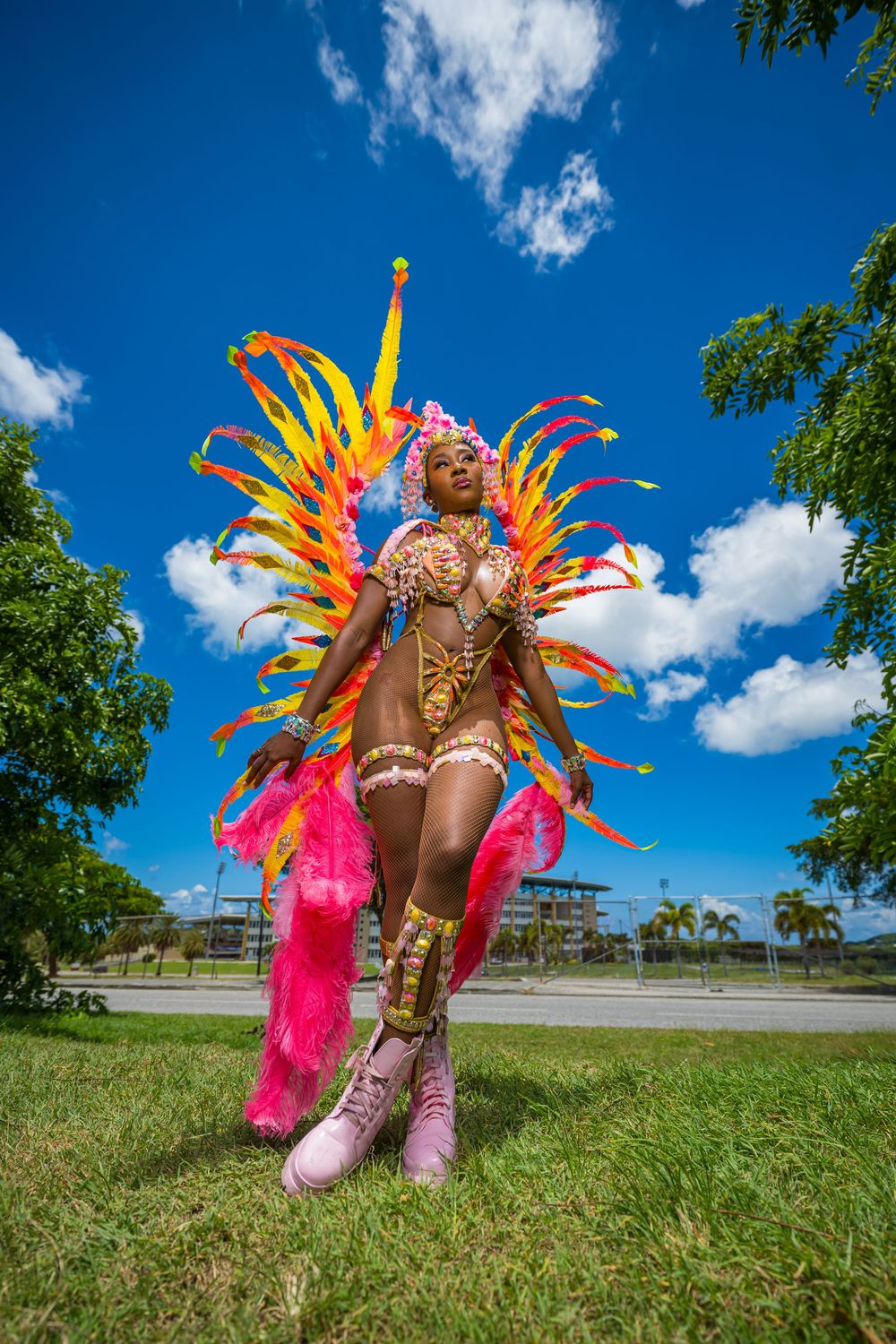 Vibrant carnival costume with orange and pink feathers photographed outdoors under blue sky.