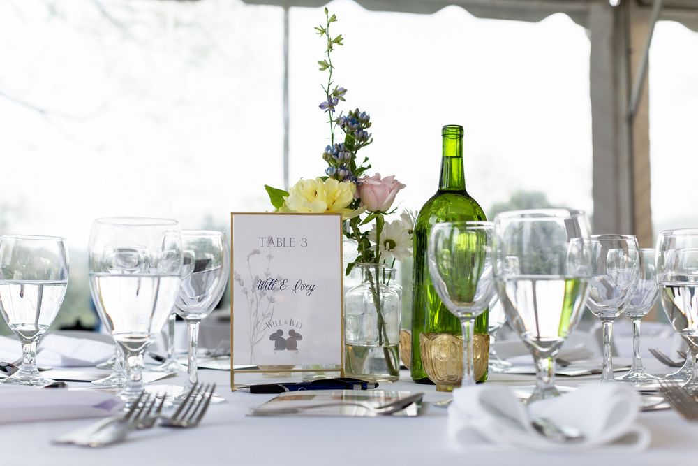 An elegant table setting with wine glasses, place cards, and floral centerpiece for a fundraiser event.