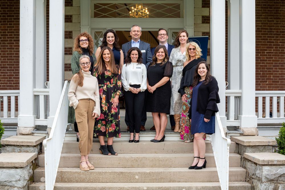 The board members of Tennessee Alliance for Kids stand together on white columned porch steps of a historic brick building.