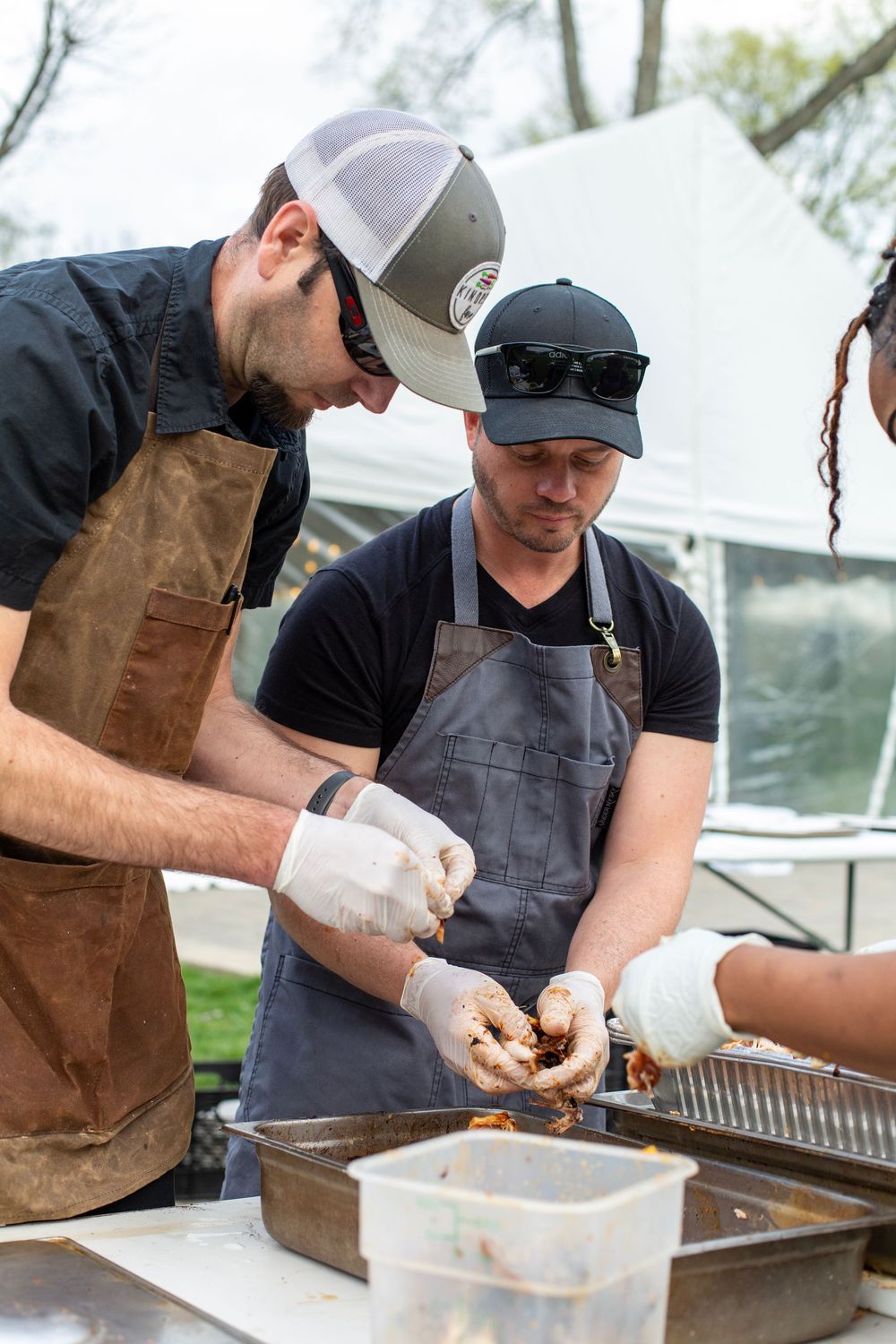 Culinary staff preparing food together at an outdoor cooking station at a fundraising event.