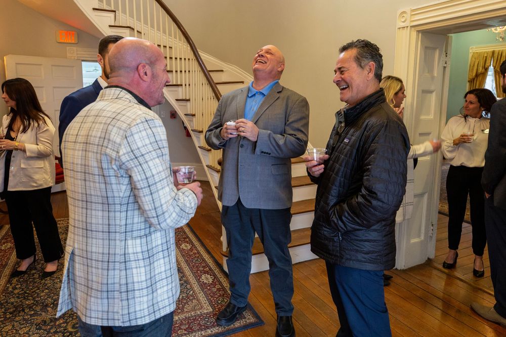 People engaged in conversation during an indoor networking event near a staircase.