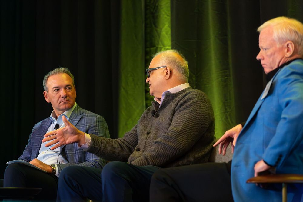 Panel discussion taking place on stage with dark green curtain backdrop.