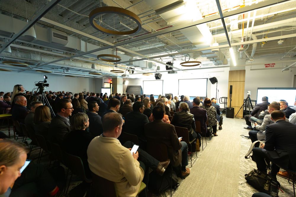 Large audience seated in modern conference room for business presentation.