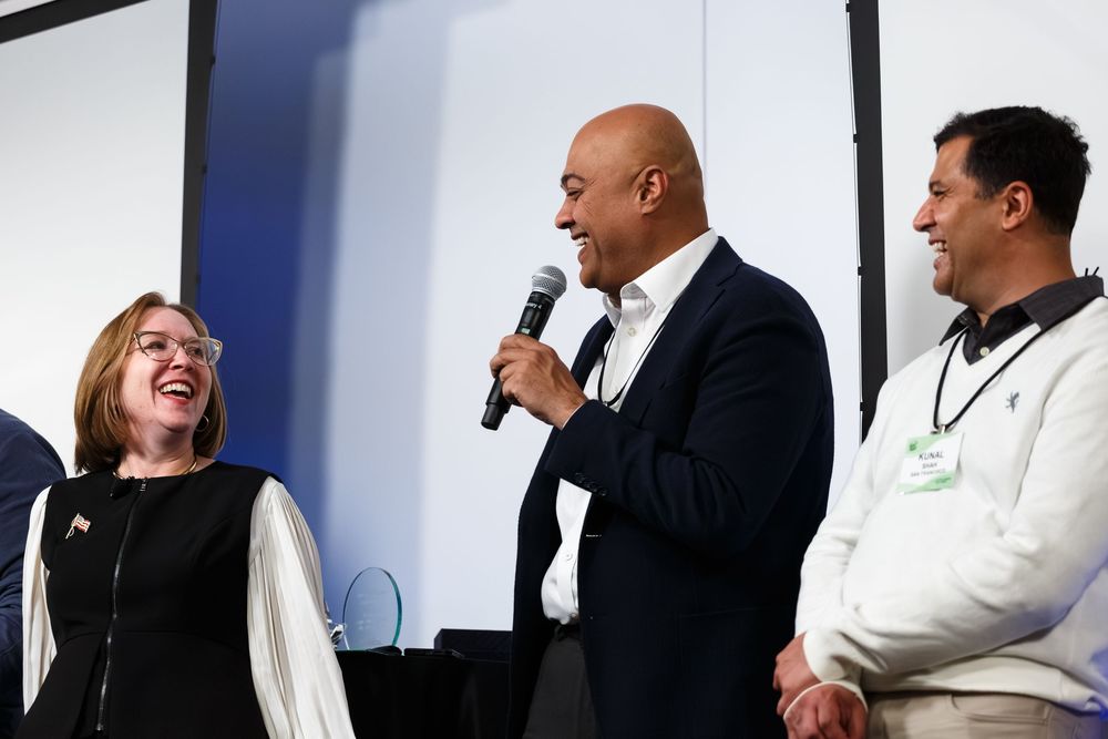 Speakers share lighthearted moment on stage during professional presentation.
