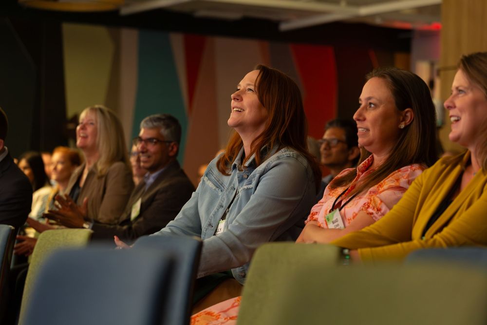 Diverse audience members react emotionally while watching a presentation at a corporate event.