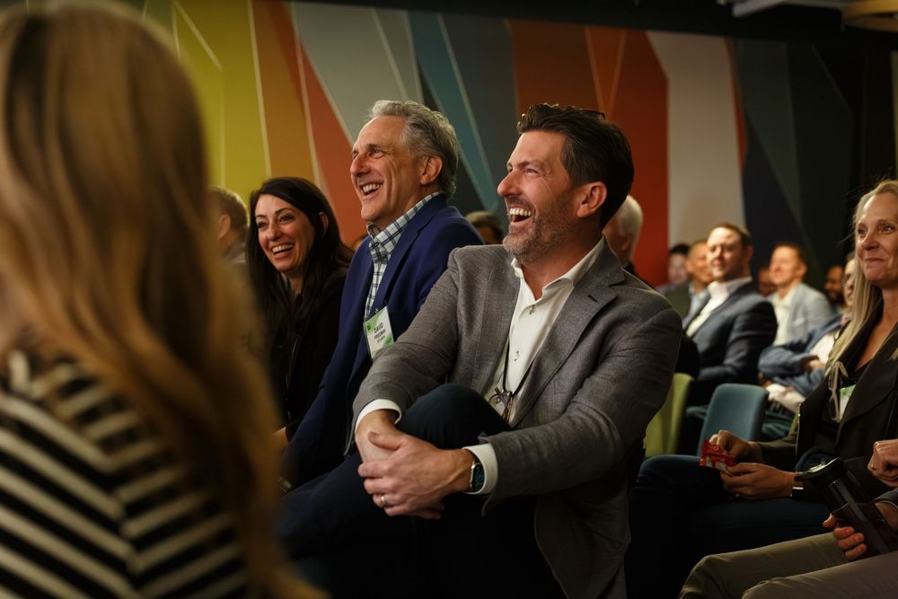 Audience members laugh and smile during an entertaining presentation at a corporate event.