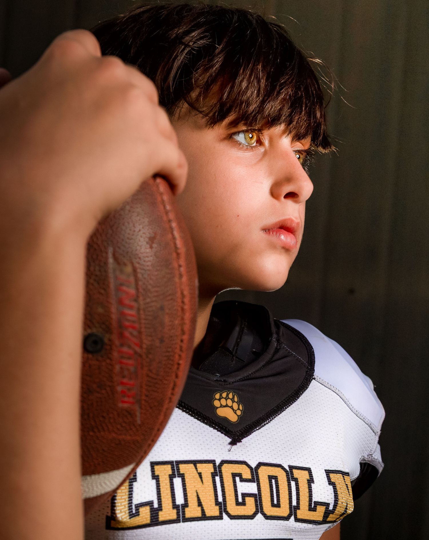 Intense youth football close-up portrait featuring Lincoln, Alabama team jersey and professional studio lighting.