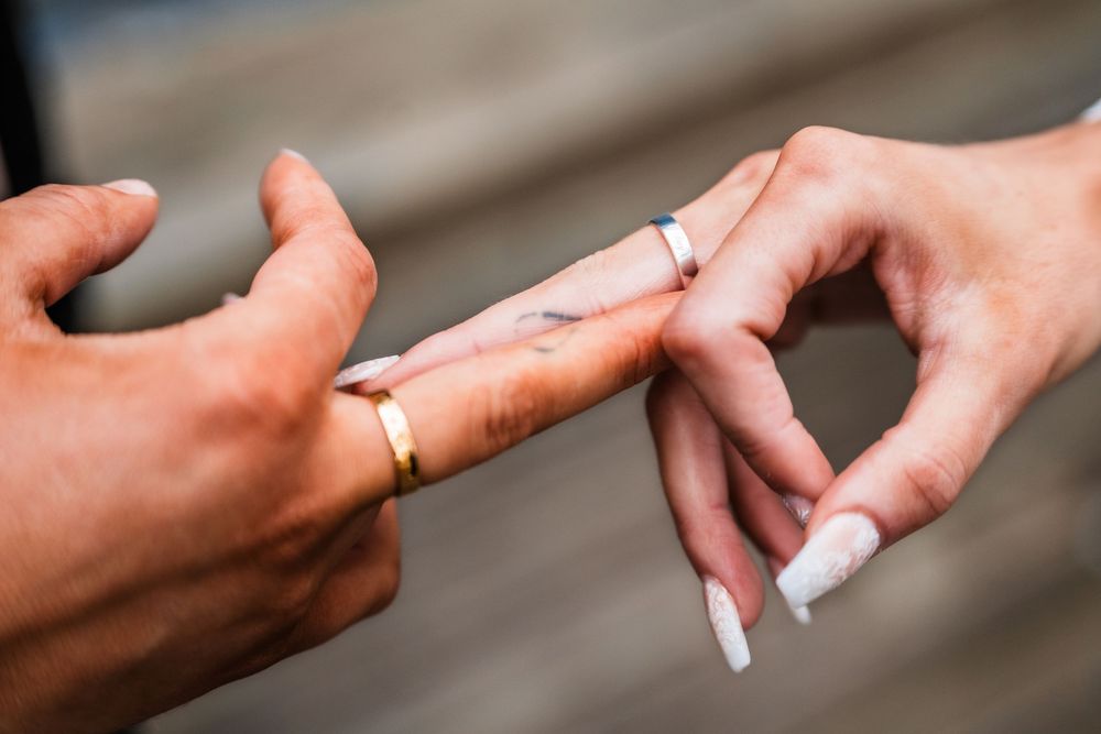 Close up of hands exchanging wedding rings during a marriage ceremony.