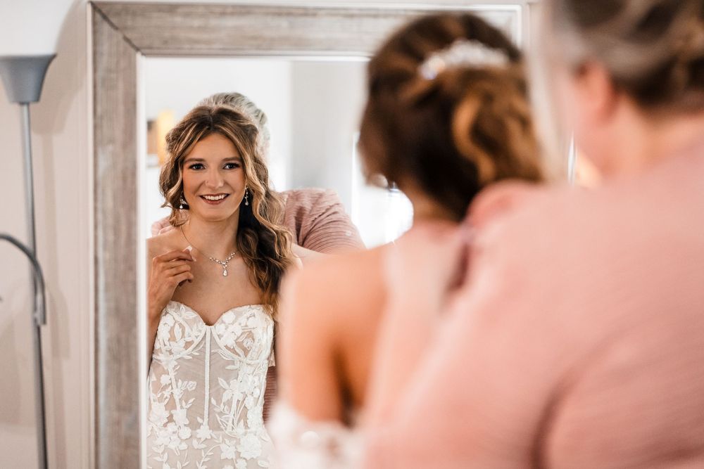 A bride admiring her reflection in mirror while getting ready.