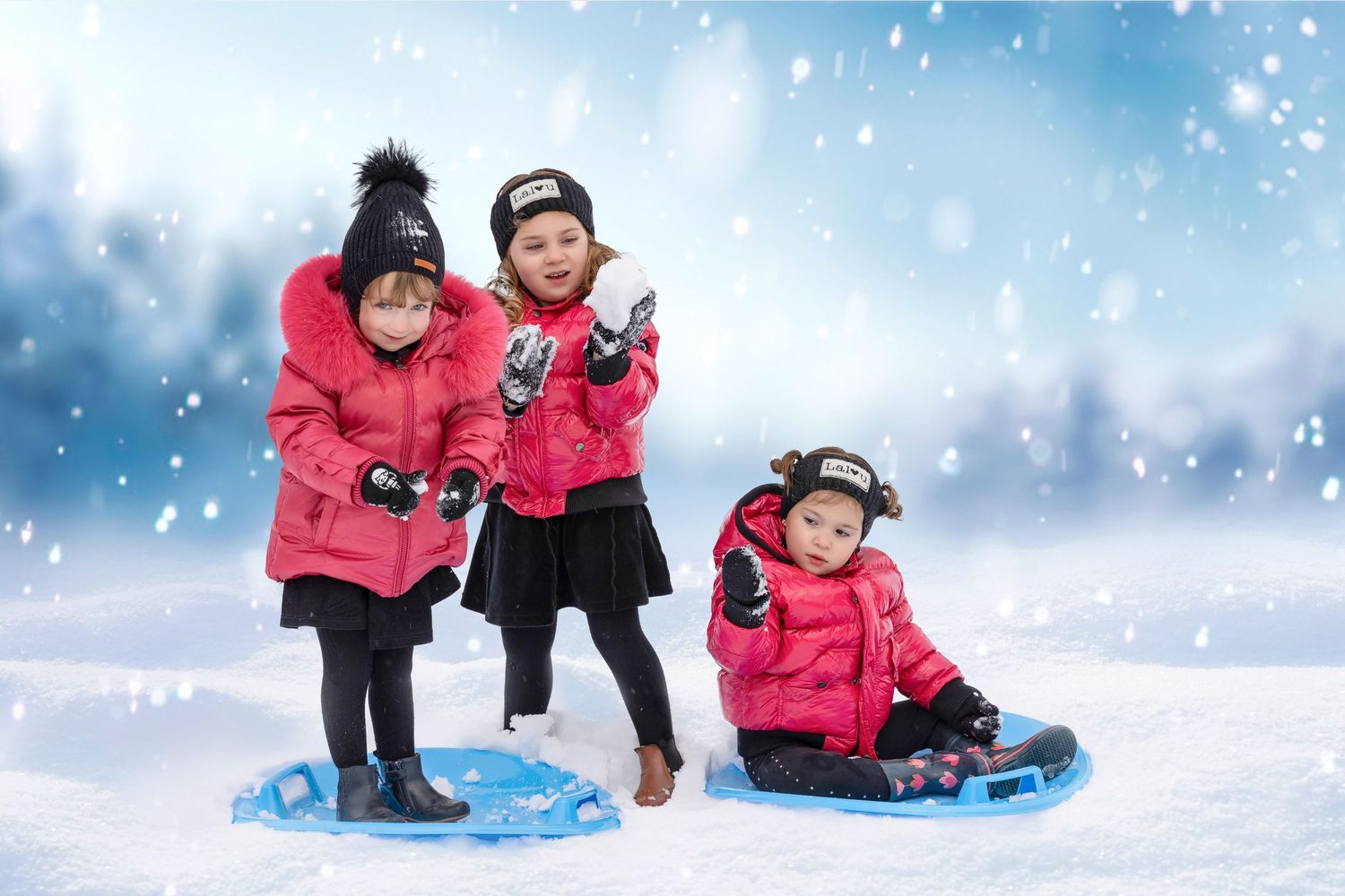 Three children in bright pink winter coats playing and sledding in the snow during a snowy winter day.