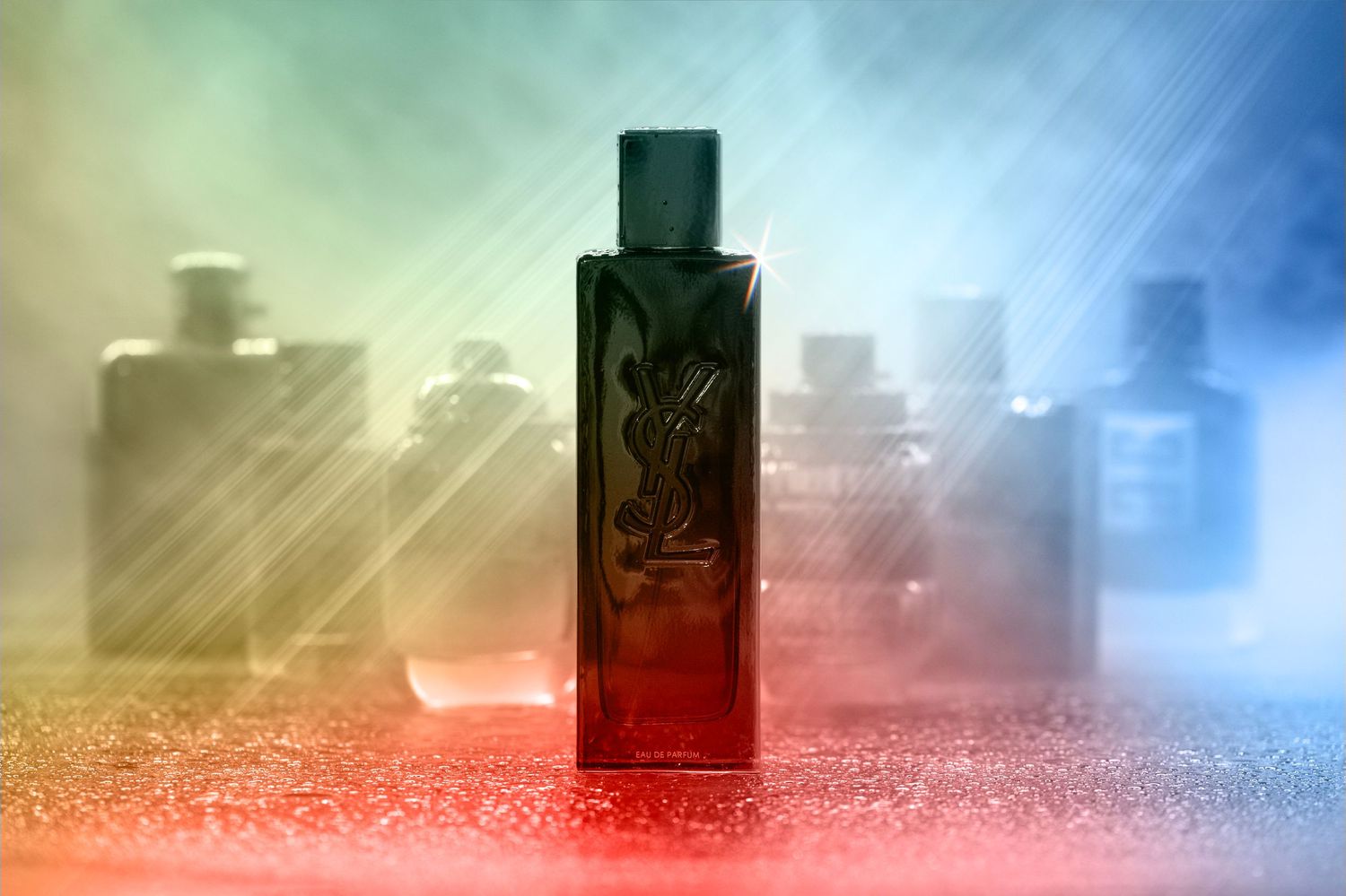 Collection of men's dark glass cologne bottles arranged on a surface with a wavy light pattern in the black-and-white background.