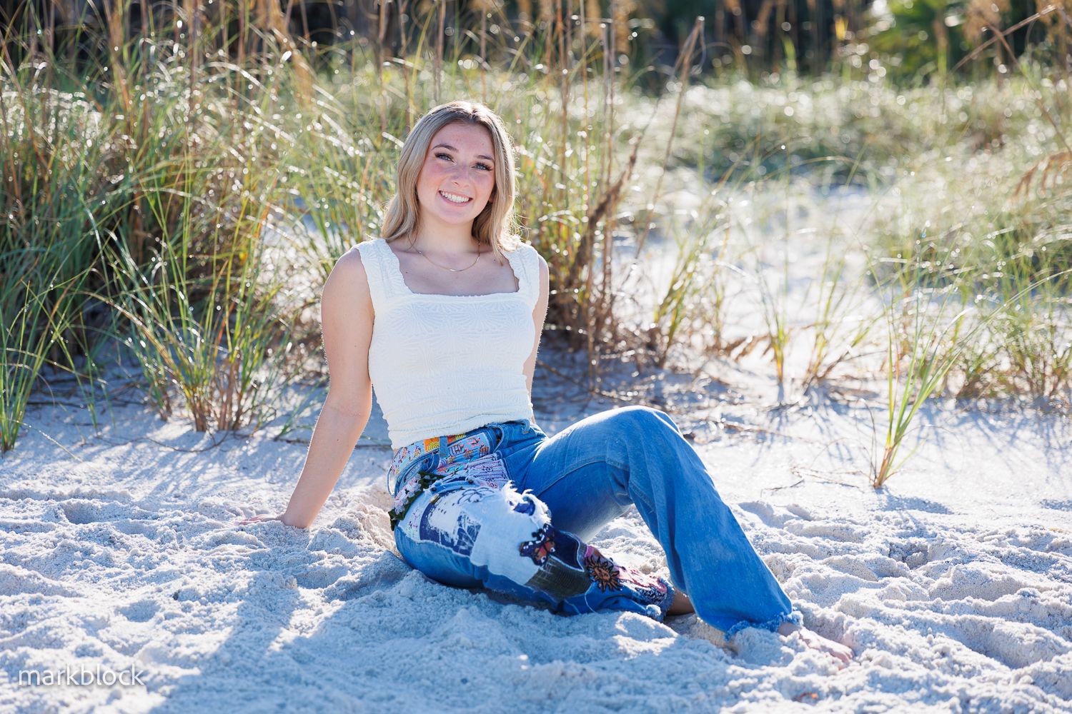 A relaxed portrait on white sand with tall beach grass and natural lighting at sunset.
