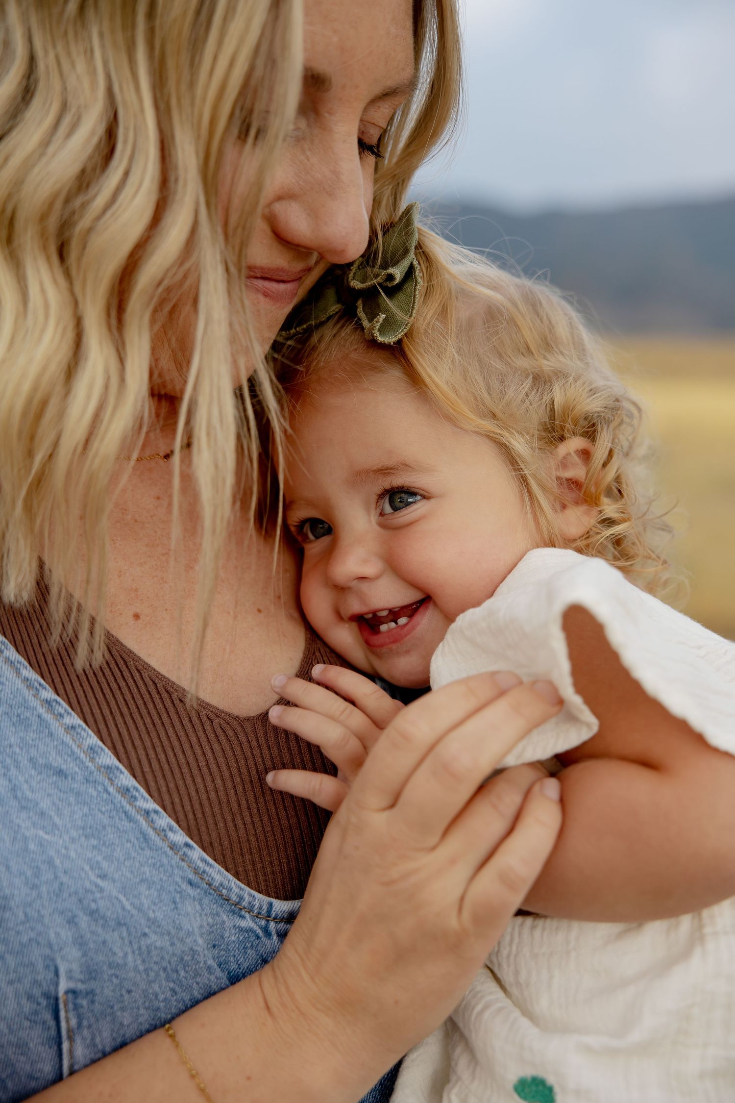 A tender moment captured between parent and child sharing laughter and embraces outdoors on a sunny day.