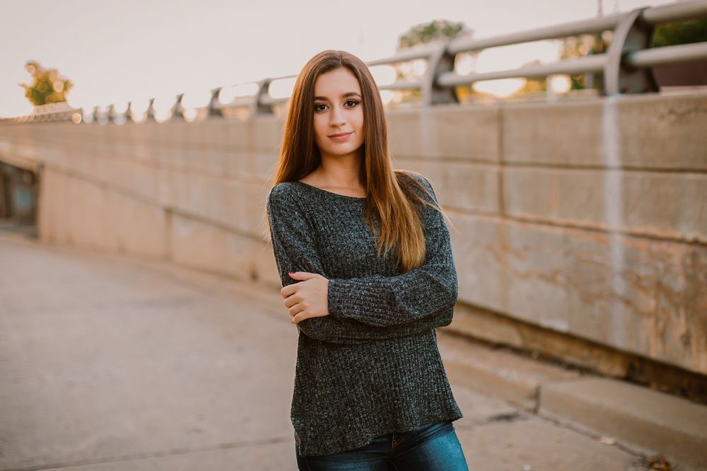 Sunset portrait session against stone wall with warm evening lighting.