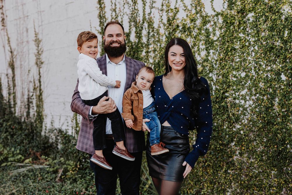 Modern family portrait against white wall with climbing vines.