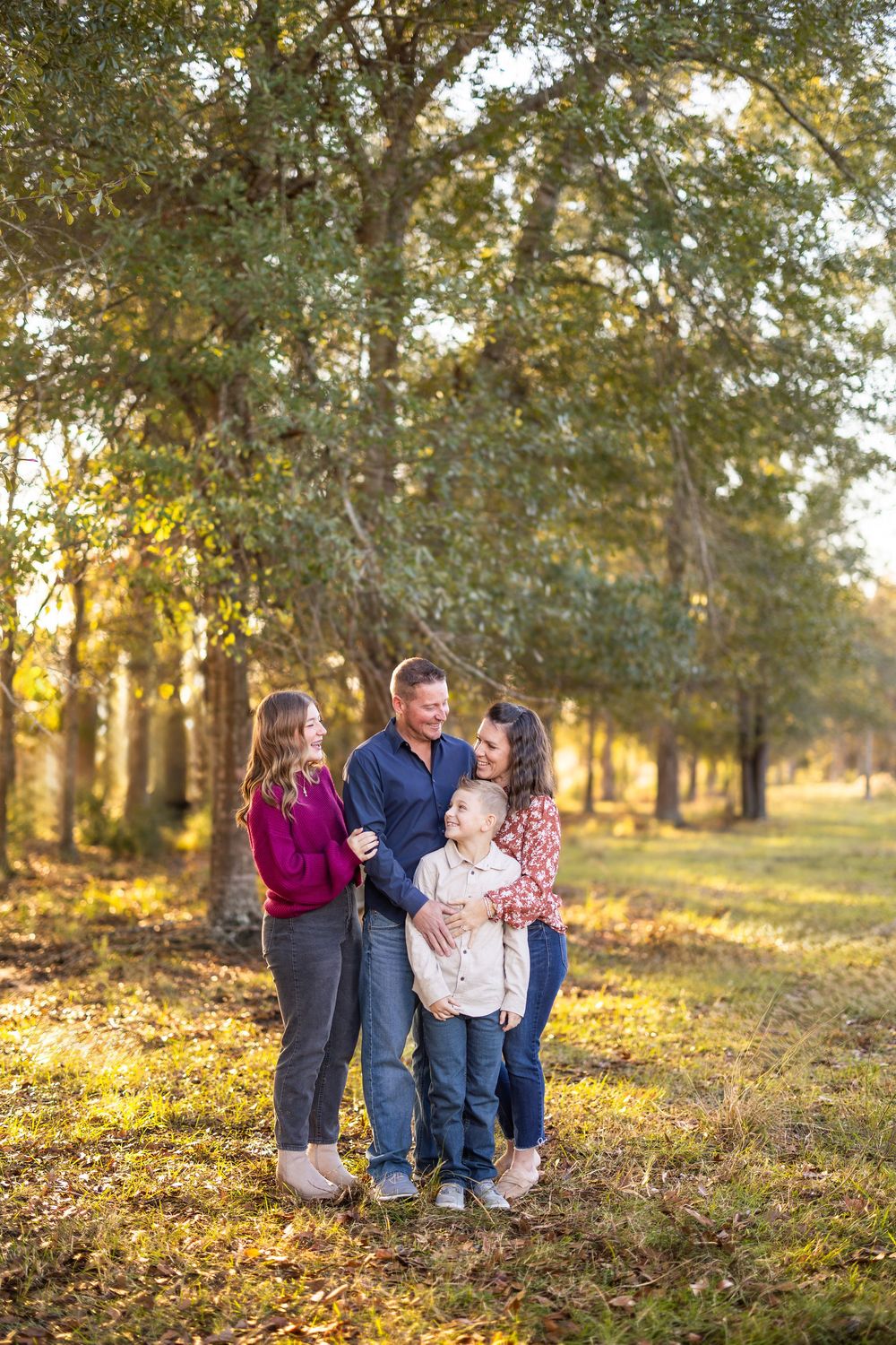 Family enjoying a warm autumn day together under golden sunlit trees in a park setting.