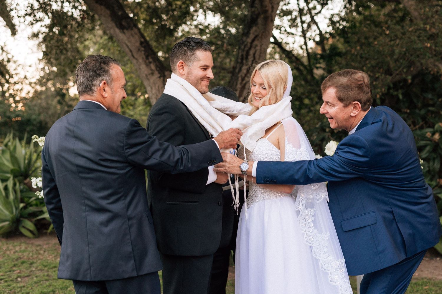 Two Fathers wrap a shawl around a wedding couple at their Santa Barbara wedding ceremony