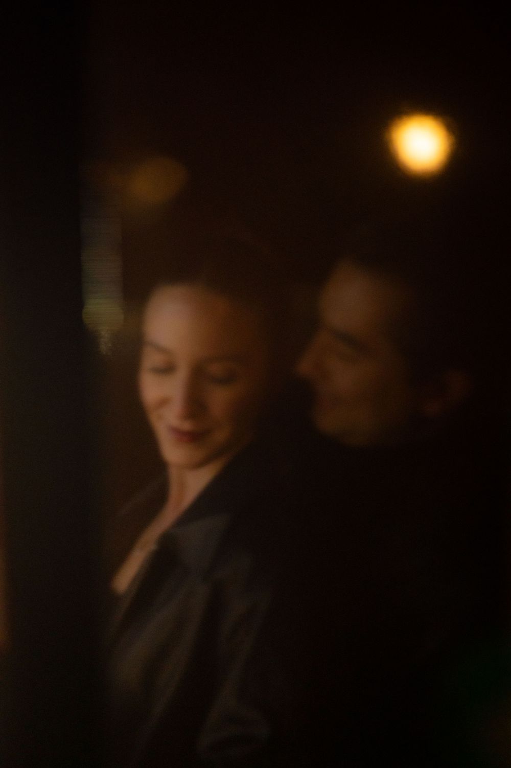 A couple shares a tender romantic moment in soft warm light in a dimly lit setting.