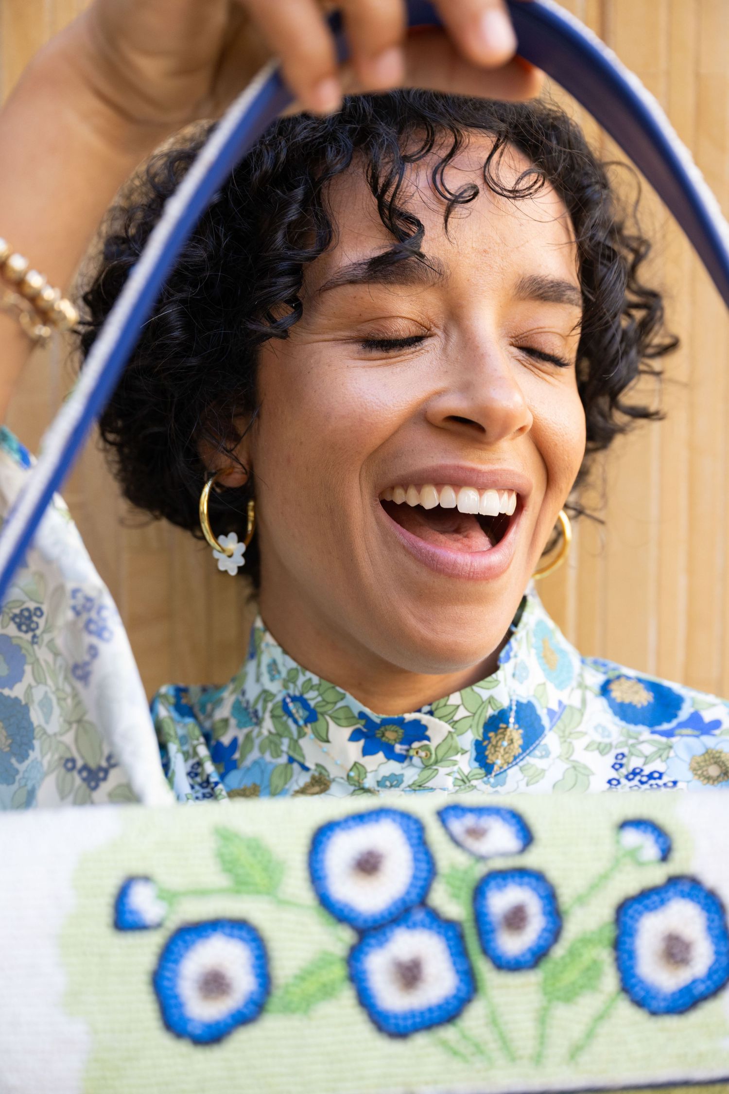 A sequence of joyful expressions captured in a series showing natural curly hair and a blue floral patterned dress.