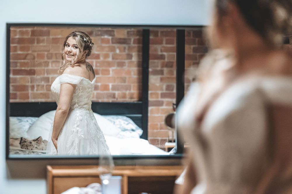 A joyful moment captured naturally of bride seeing herself for the first time on her wedding morning.