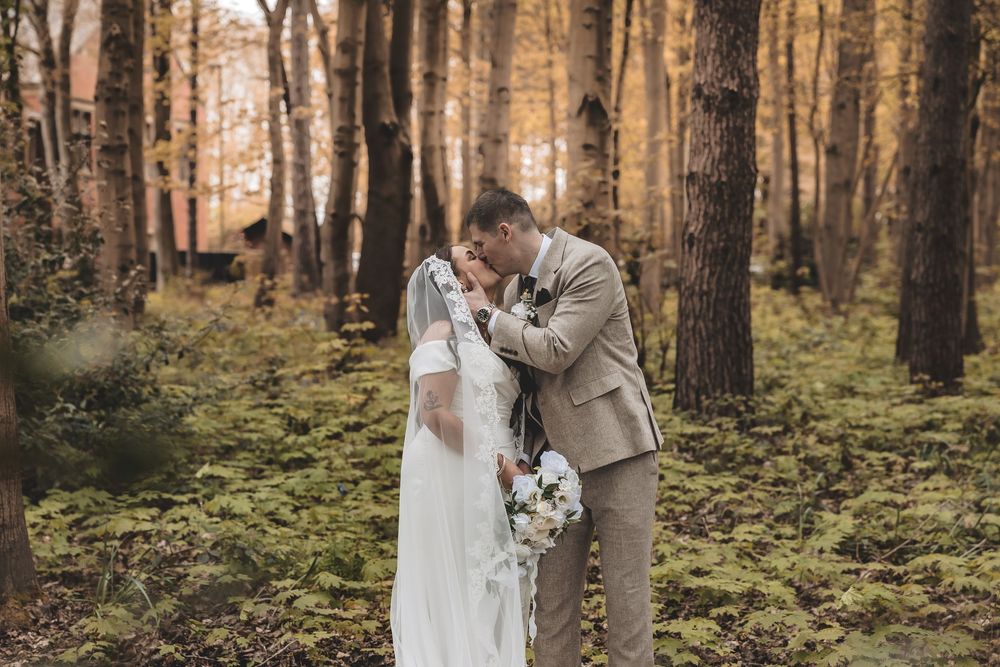 A candied couple portrait during a shared kiss in the woodlands of the Nottinghamshire wedding venue Pumping House.
