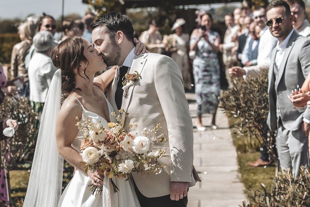 A natural unposed wedding photo of bride and groom sharing a kiss after their confetti walk.