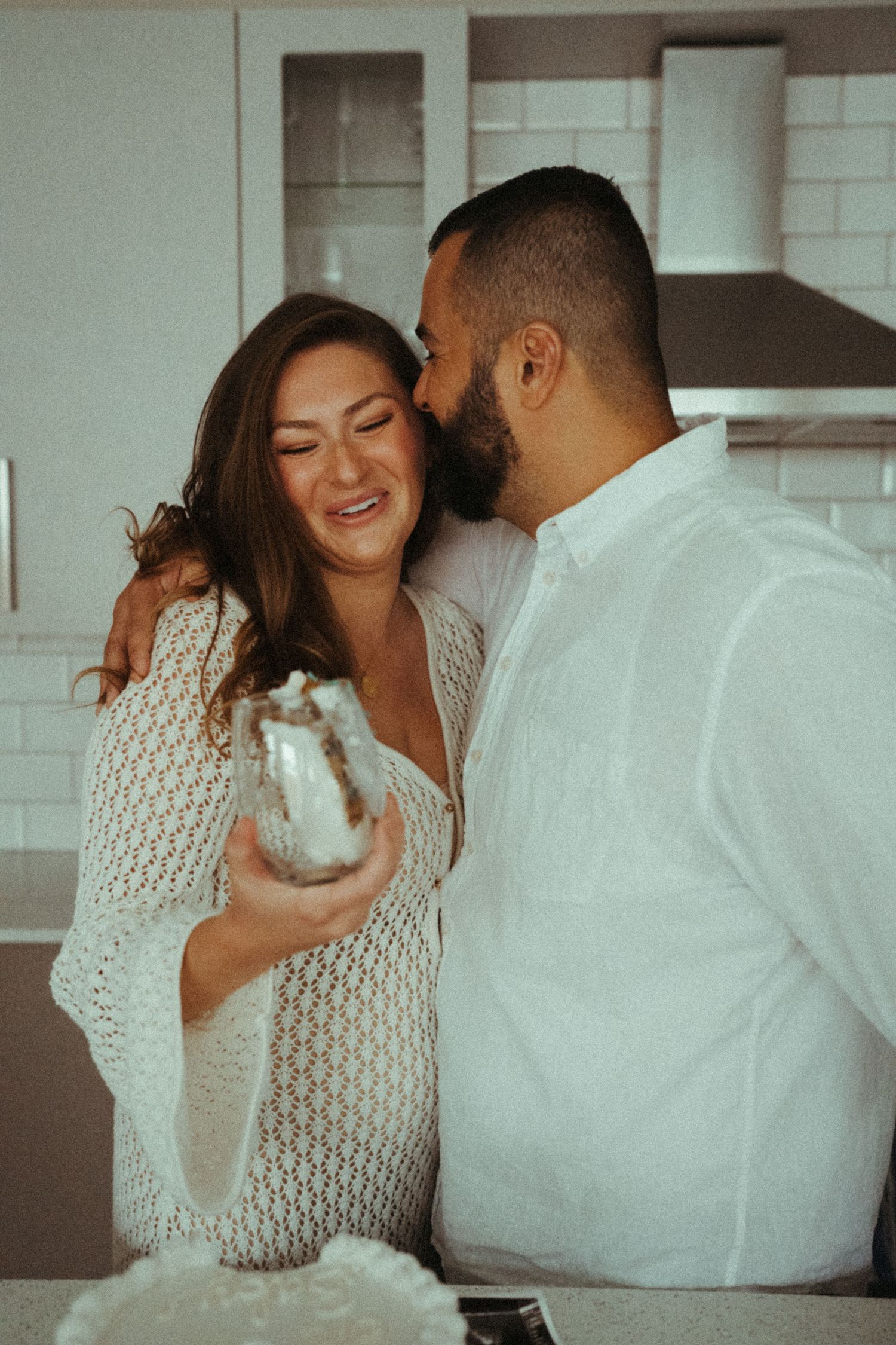 A couple shares playful moments while sitting together indoors.