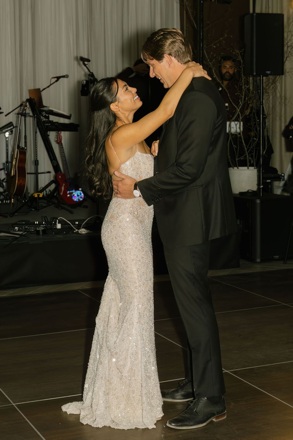 Couples dancing together during an evening wedding reception on a dark dance floor.