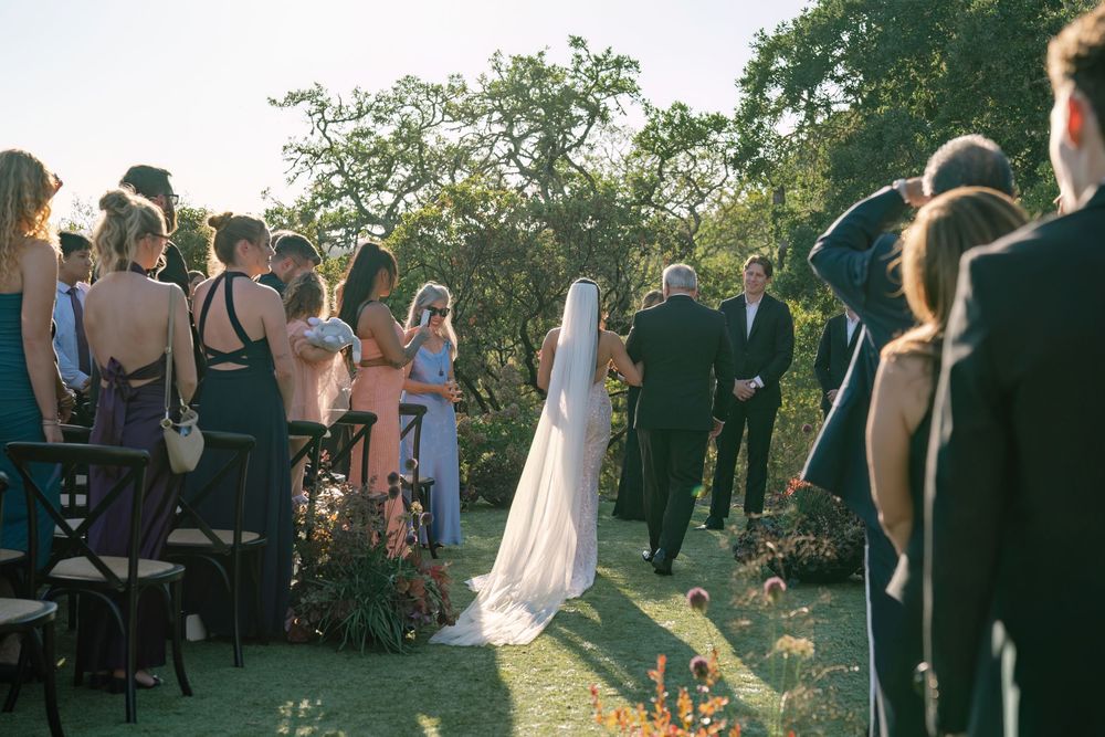 Wedding ceremony in progress with guests seated and couple at the altar in golden sunlight.