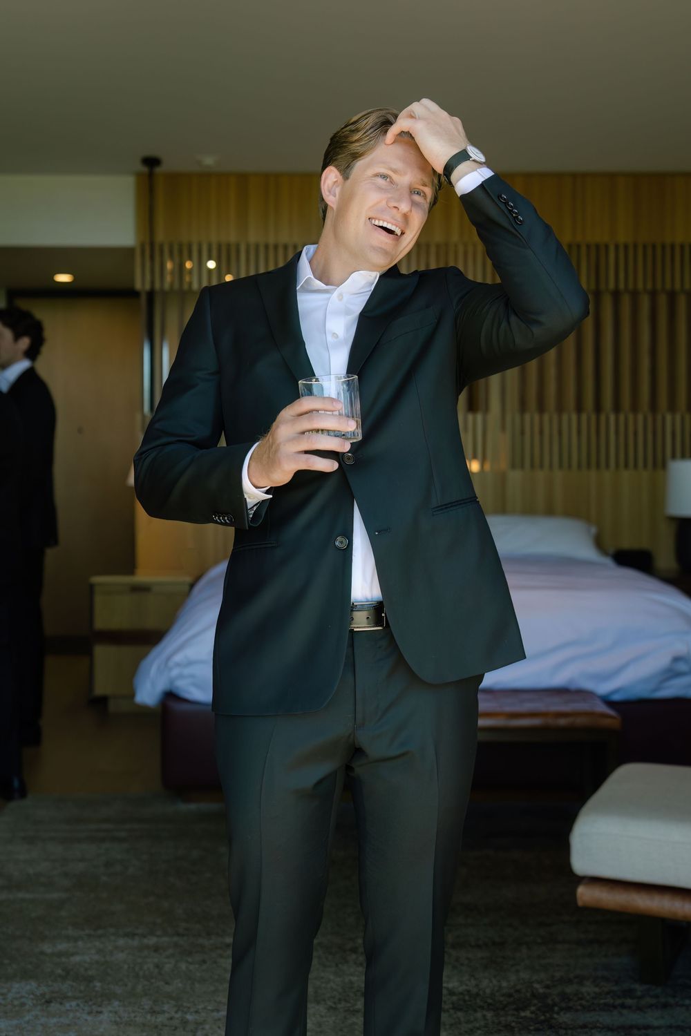 Men in formal attire playfully pose and laugh during pre-wedding preparations.