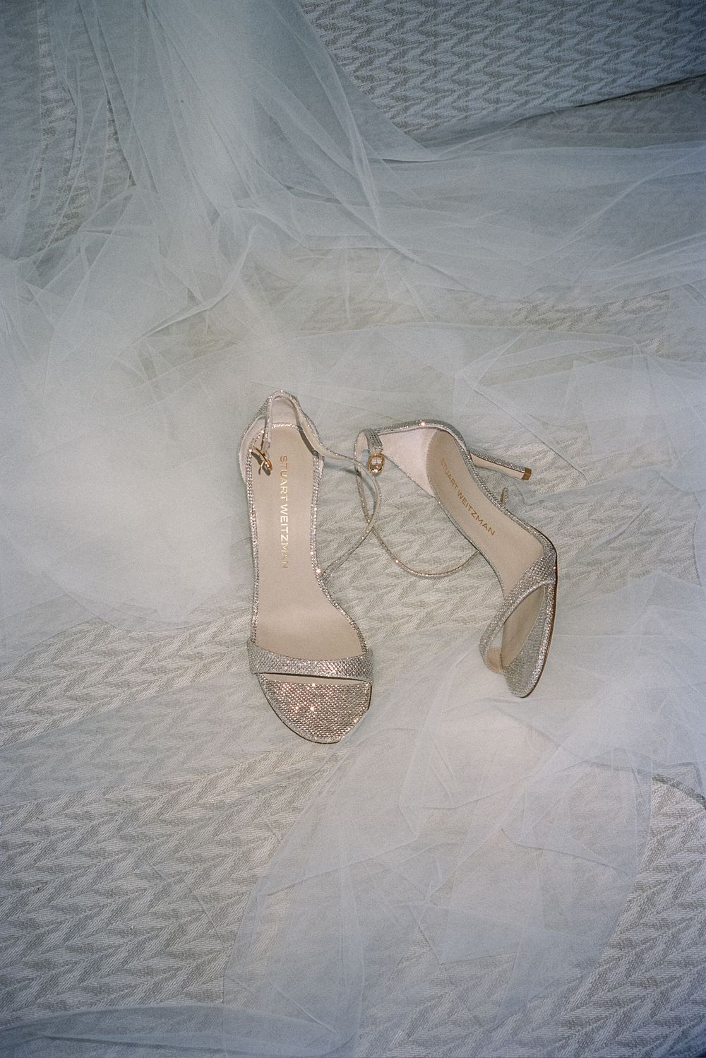 Sparkly beige wedding shoes photographed on white textured fabric.