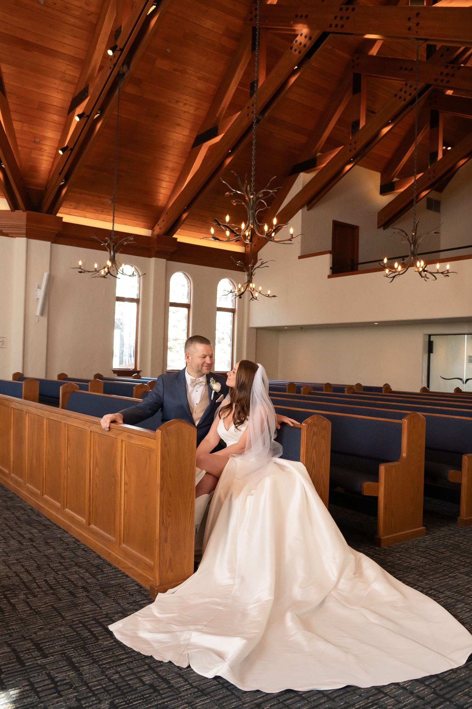 A wedding couple sits together in a church sanctuary with wooden pews and exposed beam ceilings at The Beaver Creek Chapel
