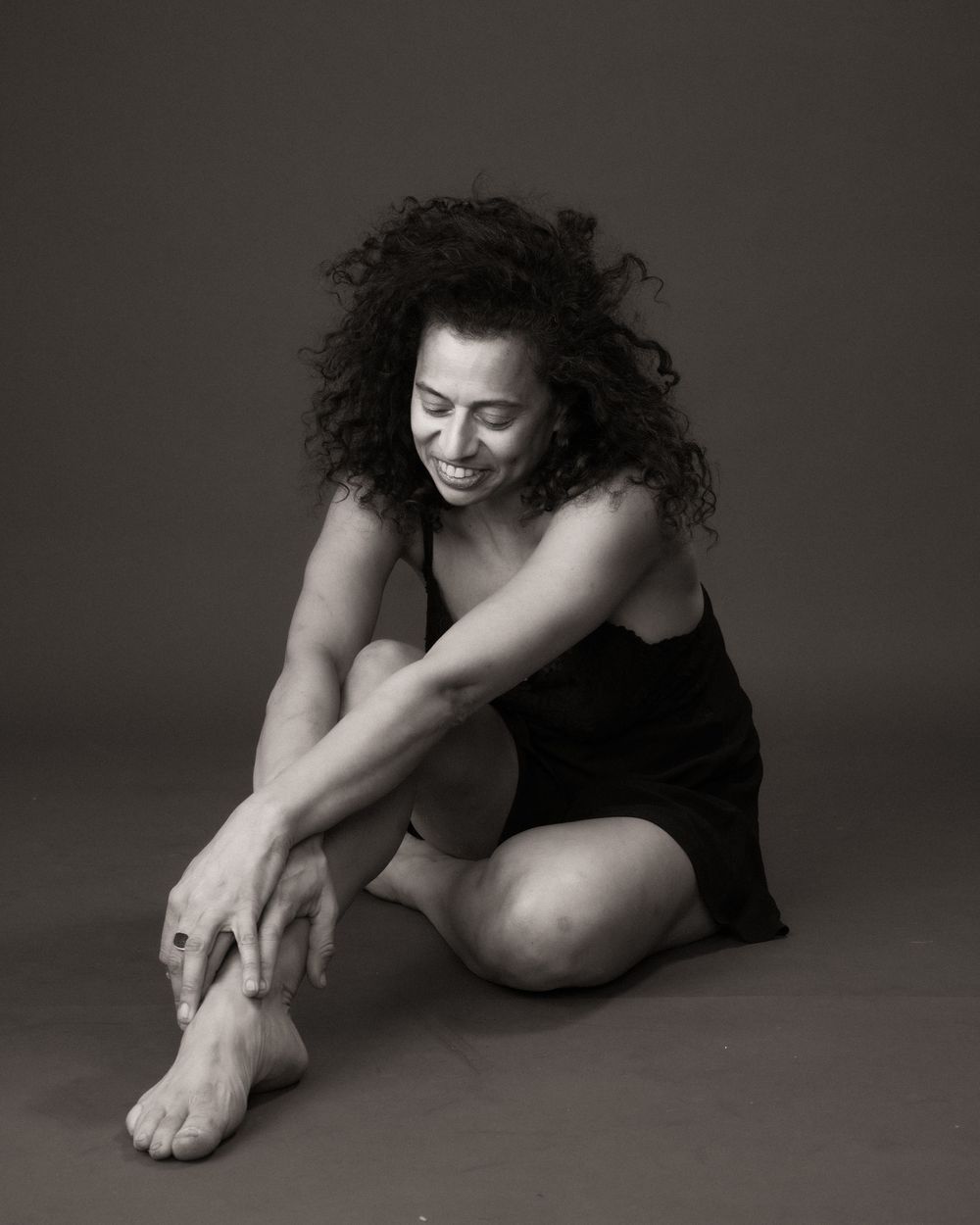 Black and white artistic photo series showing a person in dark clothing sitting on floor in various contemplative poses.