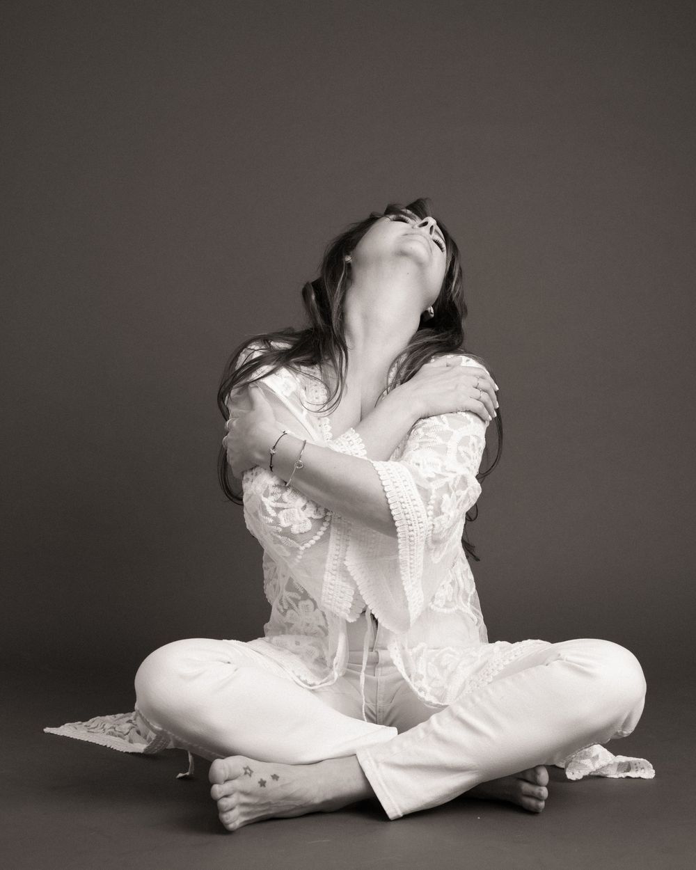 Series of artistic black and white photos showing a figure in white clothing posed in various reclining positions.