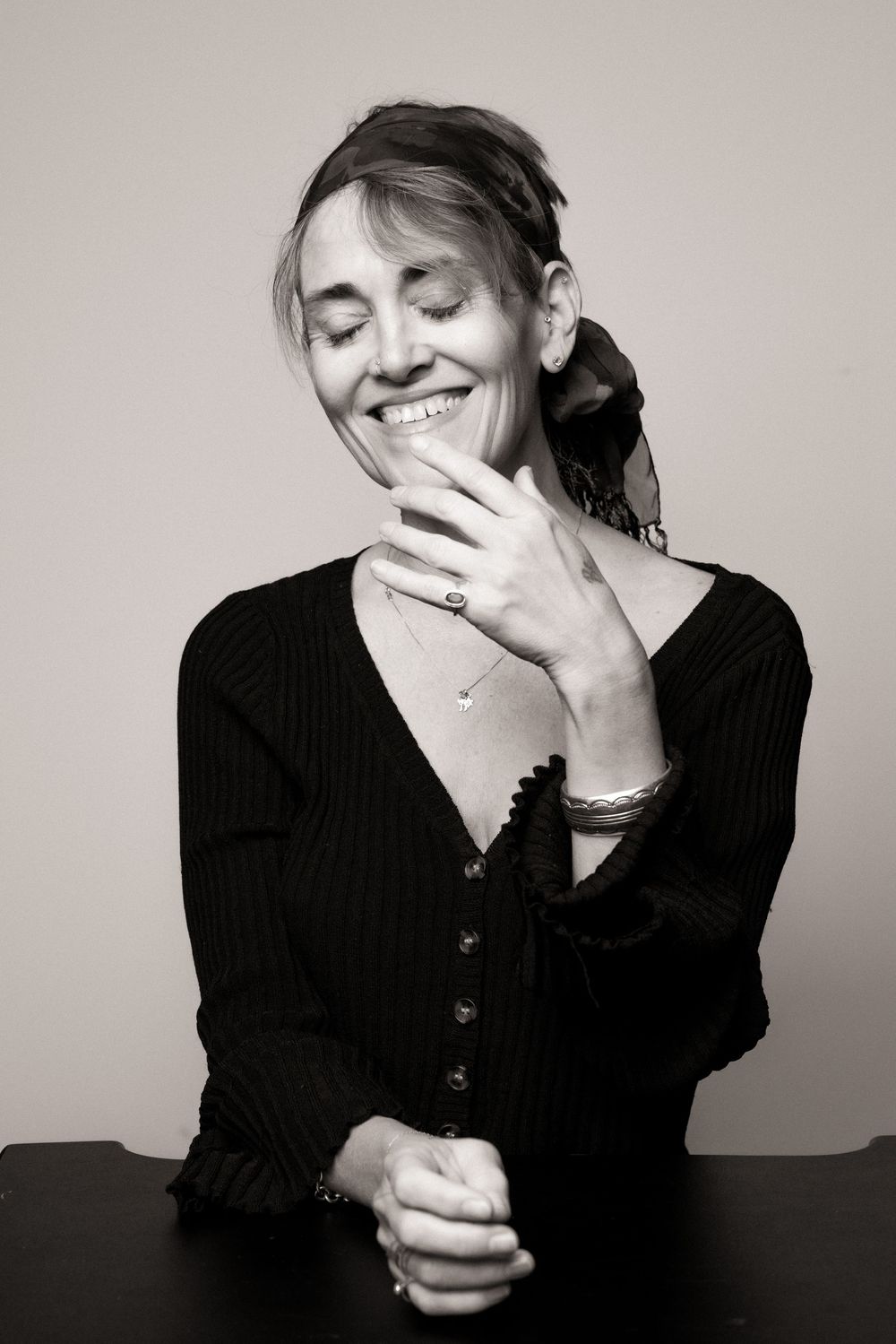 A series of black and white photos showing a person in a black sweater expressing joyful laughter against a light background.