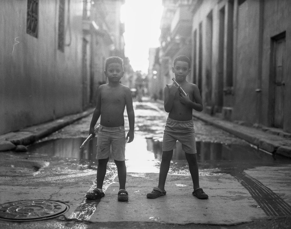 Silhouetted figures walking down a sunlit urban street.
