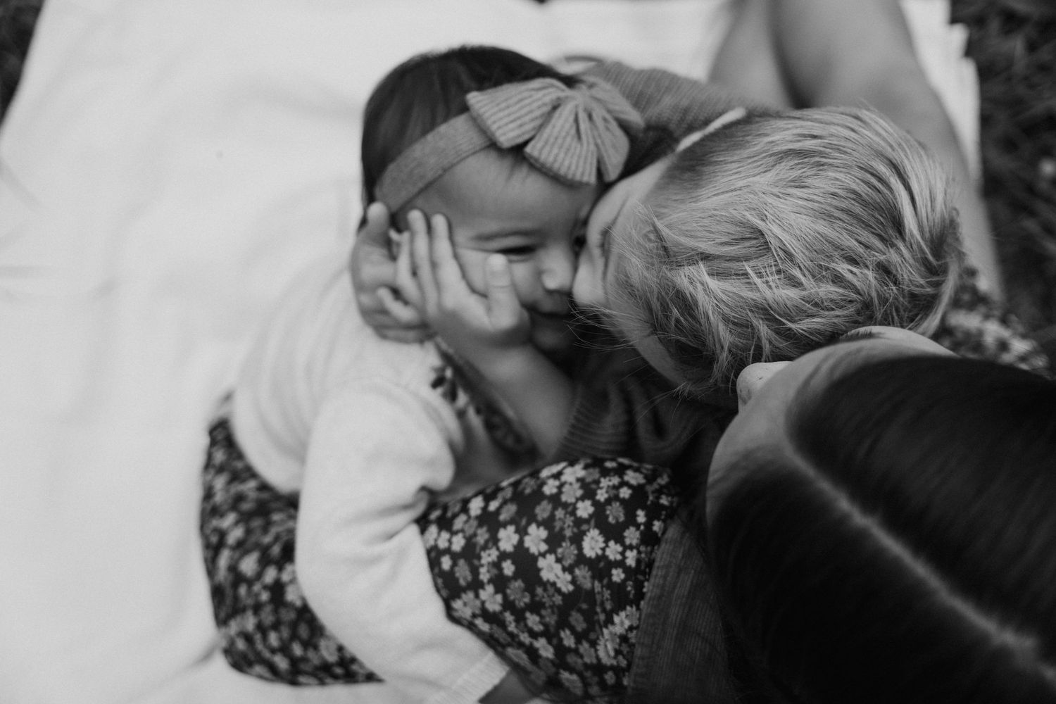 A black and white candid photo shows two people sharing a tender moment while sitting together.