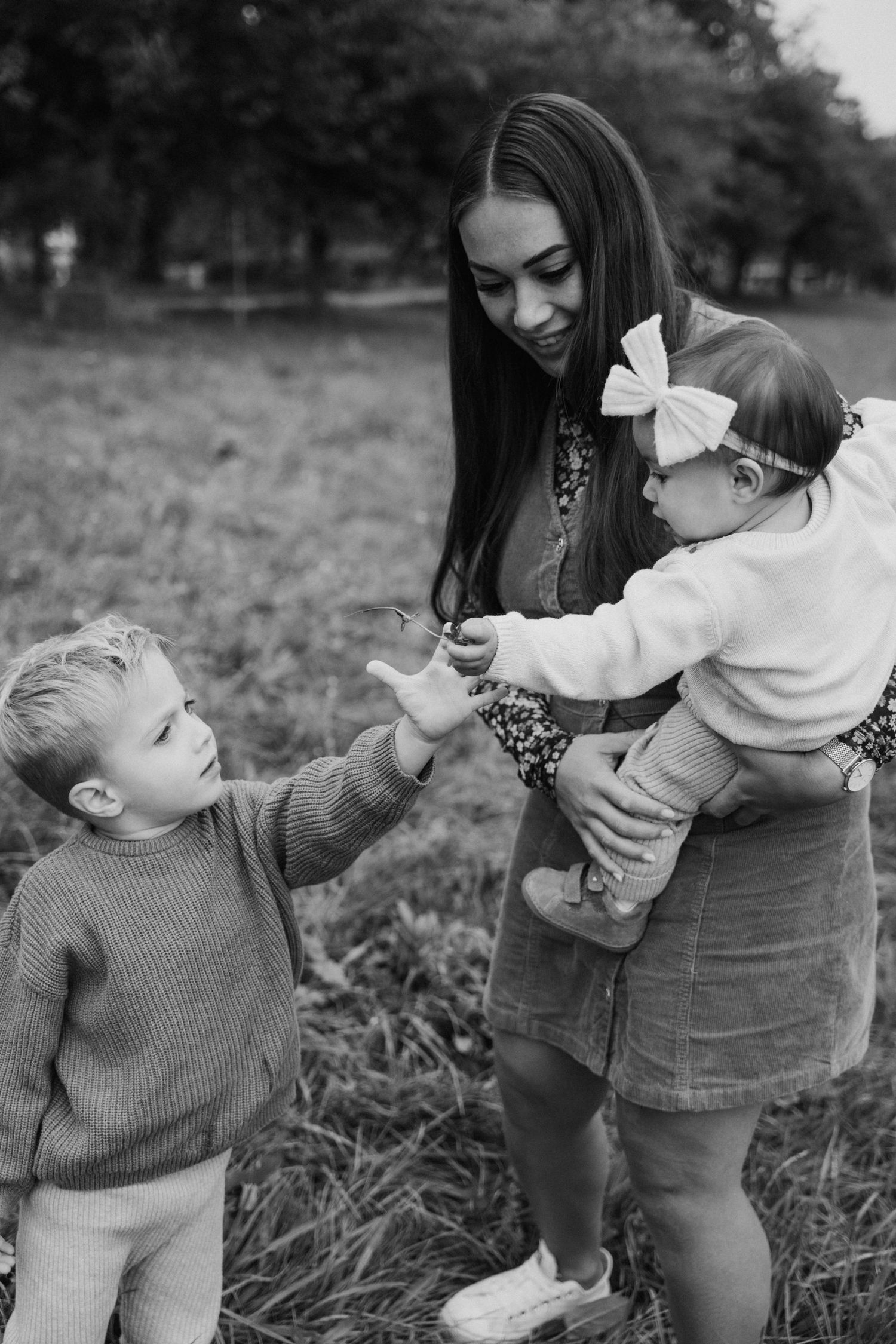 A sequence of black and white photos showing a playful interaction between a parent and child in a grassy field.