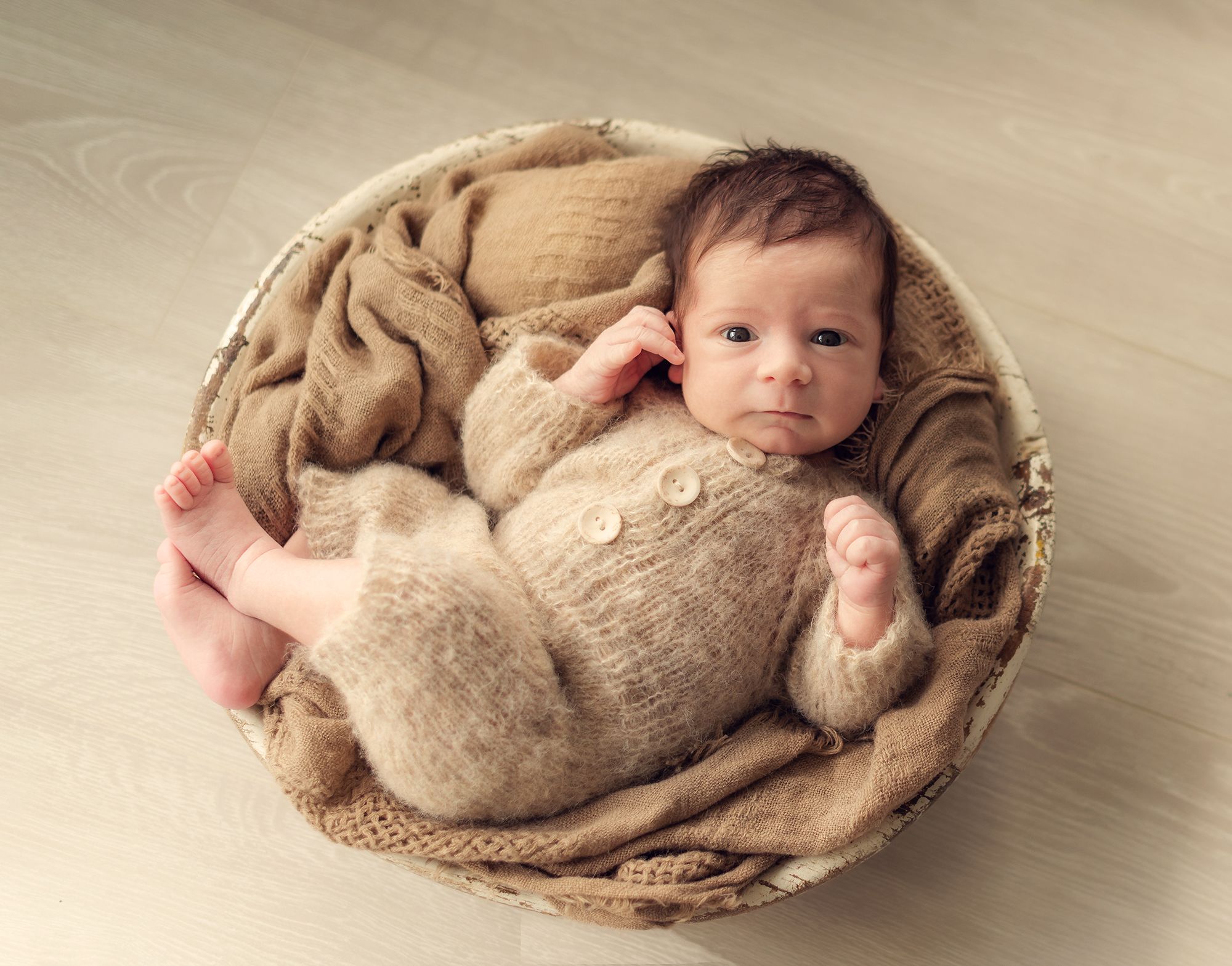 Newborn photography collage showing baby wrapped in beige blanket in different sleeping poses on wooden floor.