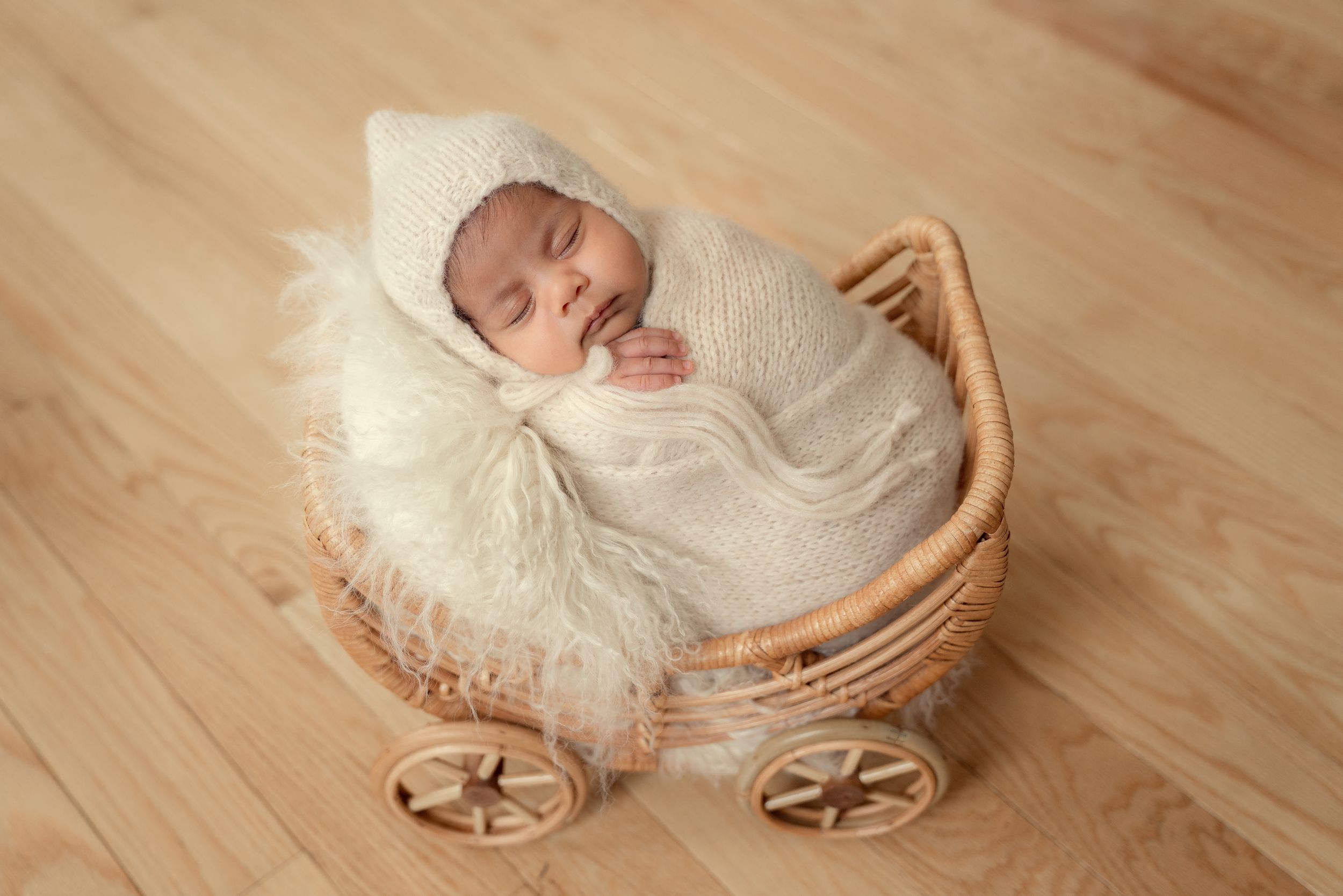 A series of newborn baby photos showing peaceful sleeping poses in a rustic wooden basket on hardwood flooring.