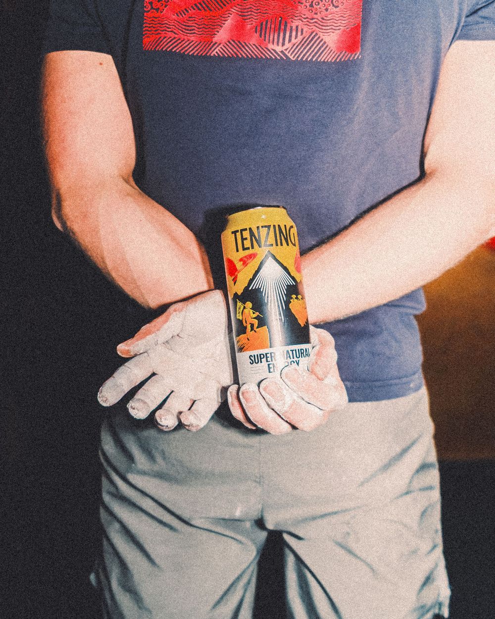 Hands holding a Ten Junk Miles beer can against a backdrop of gray pants.