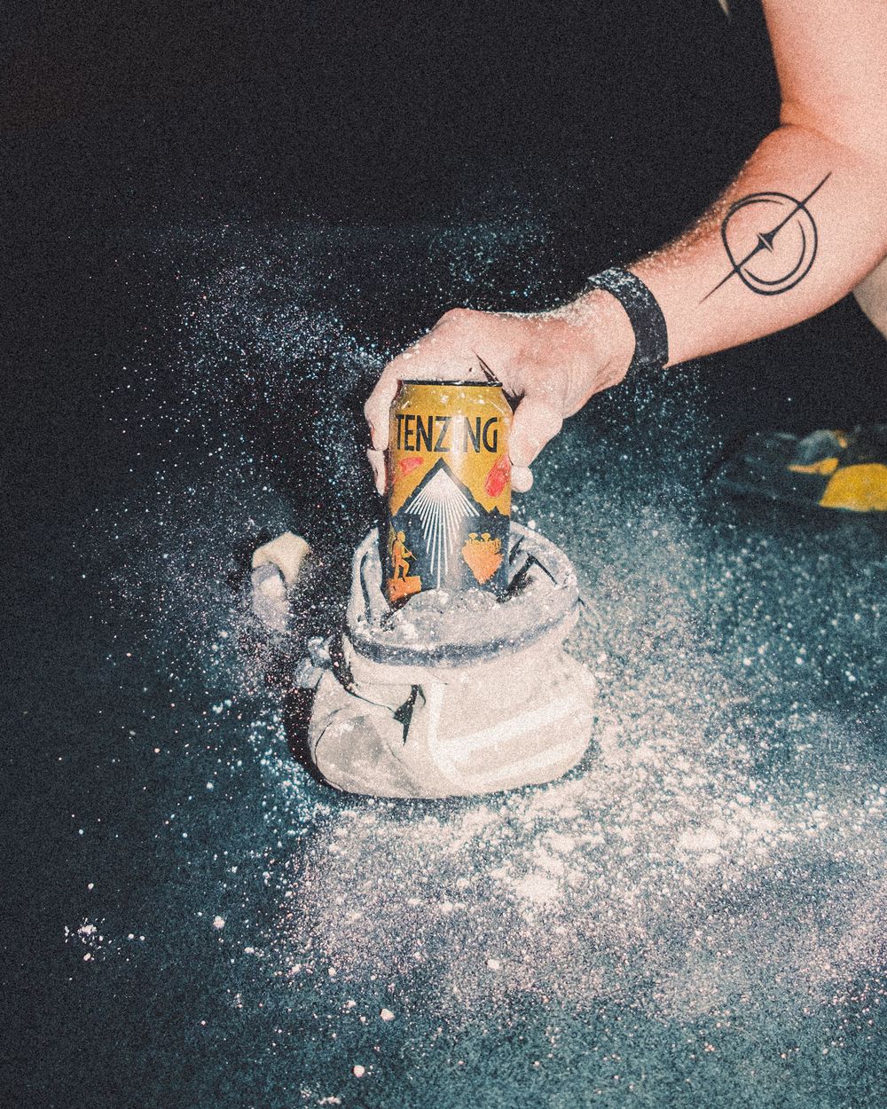 A hand places a Benzinga drink can into a pile of white powder creating a splash effect against a dark background.