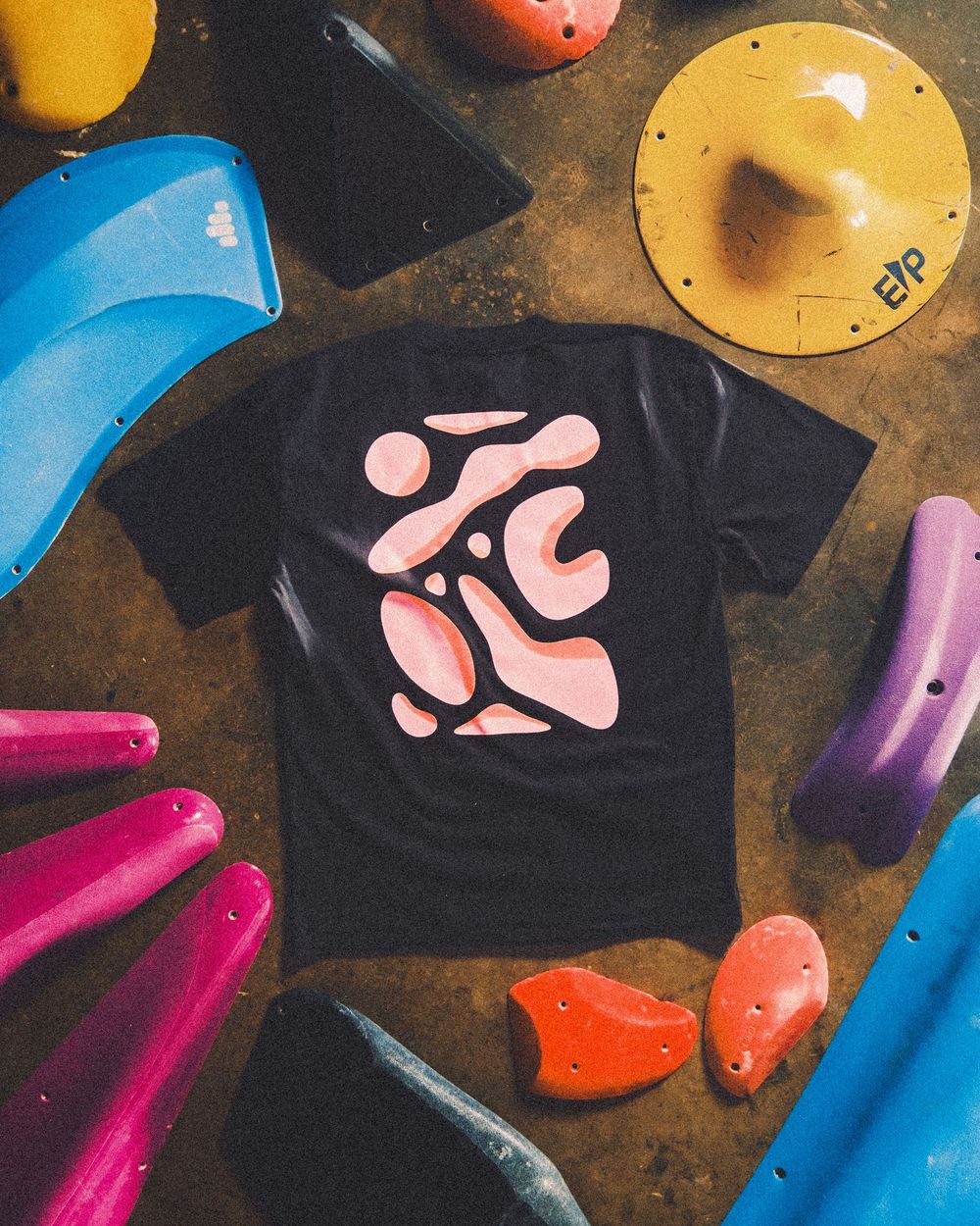 Climbing wall holds in vibrant colors including blue, pink, yellow and orange mounted against a dark background.