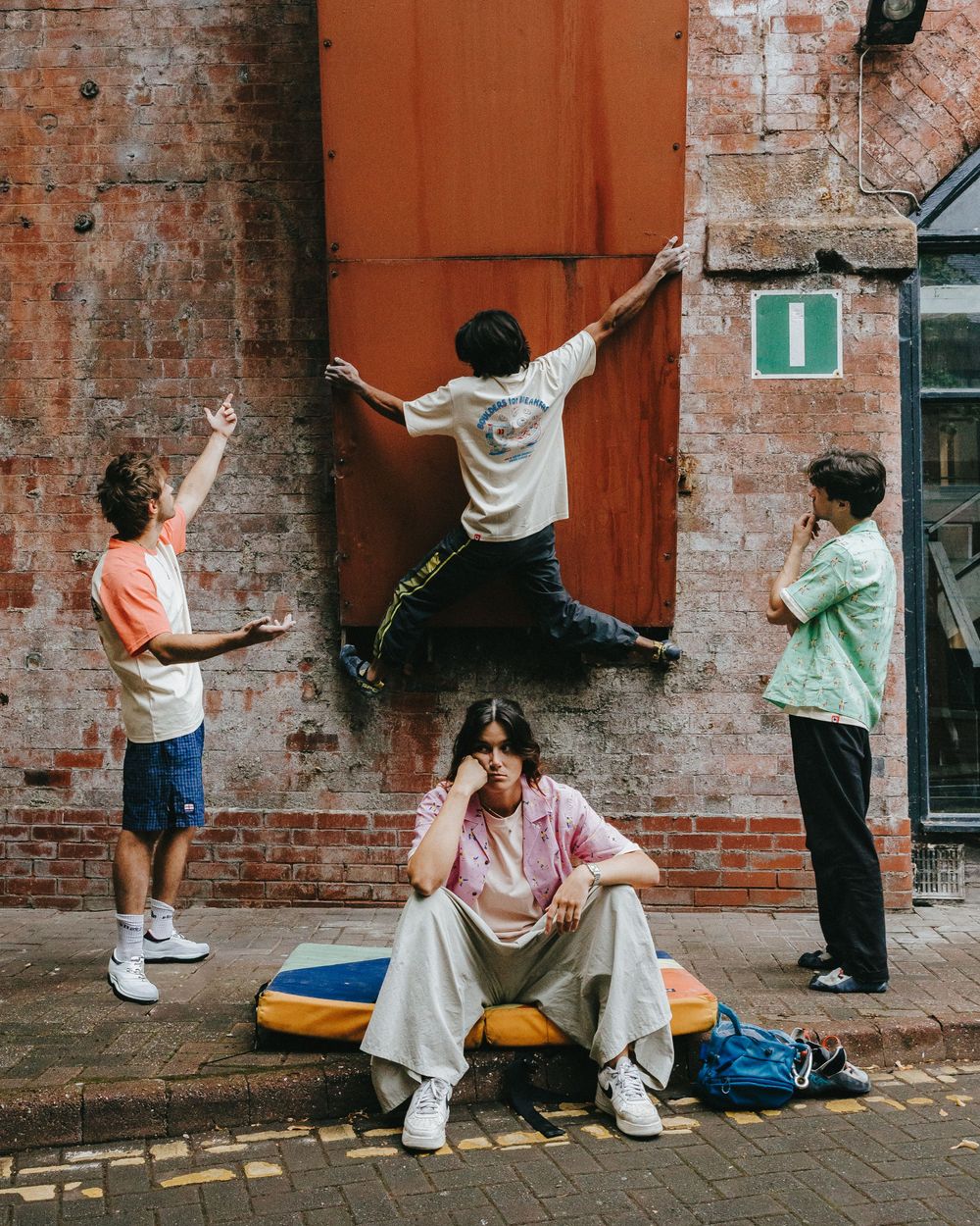 A series of five connected photos showing people dancing and posing against a rustic brick wall backdrop.