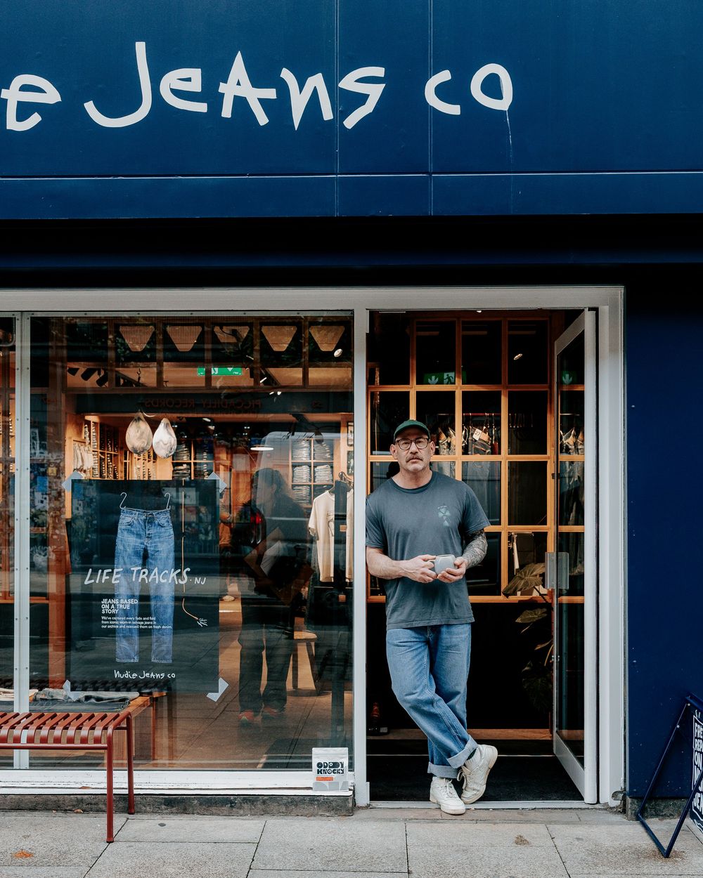 A series of storefront windows showing a denim and jeans retail shop with blue tinted lighting and signage.