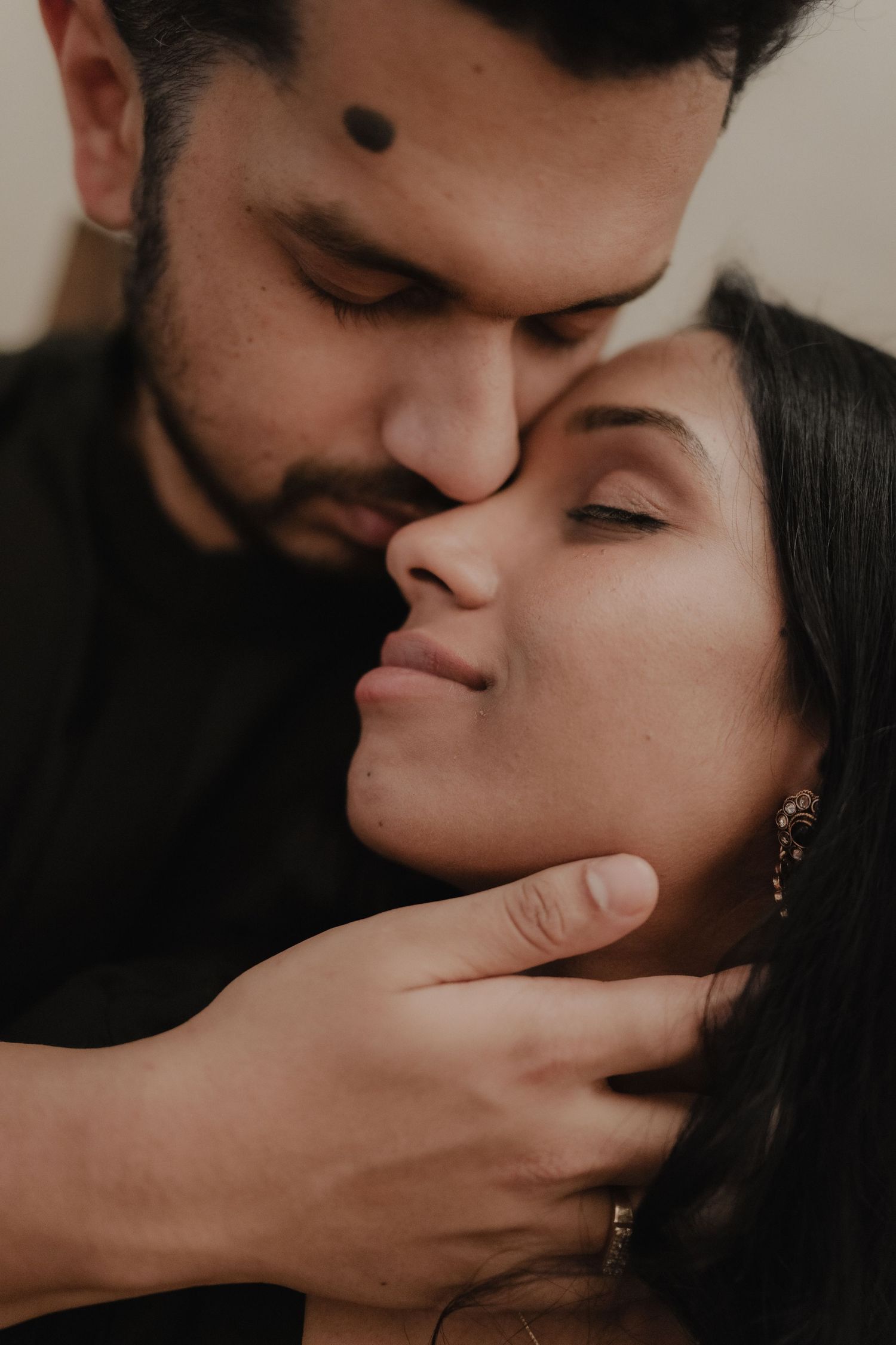 A couple sharing an intimate moment, man tenderly holding womans face as they lean close together.