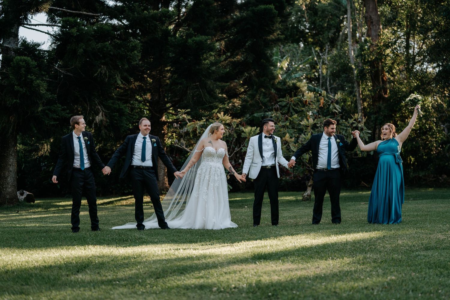 Wedding party poses for a panoramic sequence of photos in a scenic outdoor park setting during golden hour.