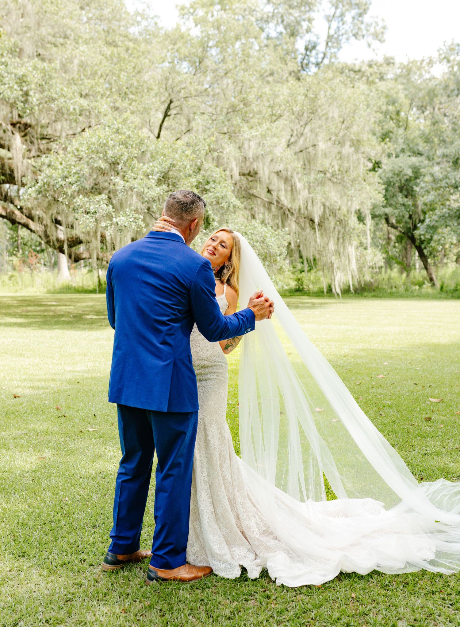 Romantic wedding couple with flowing long veil in lush garden setting.